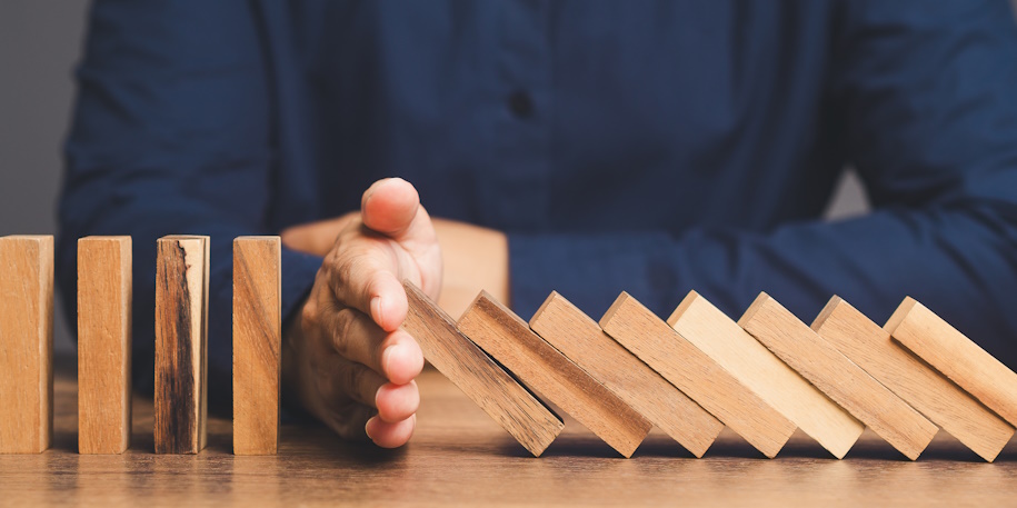 person blocking wooden dominoes with their hand