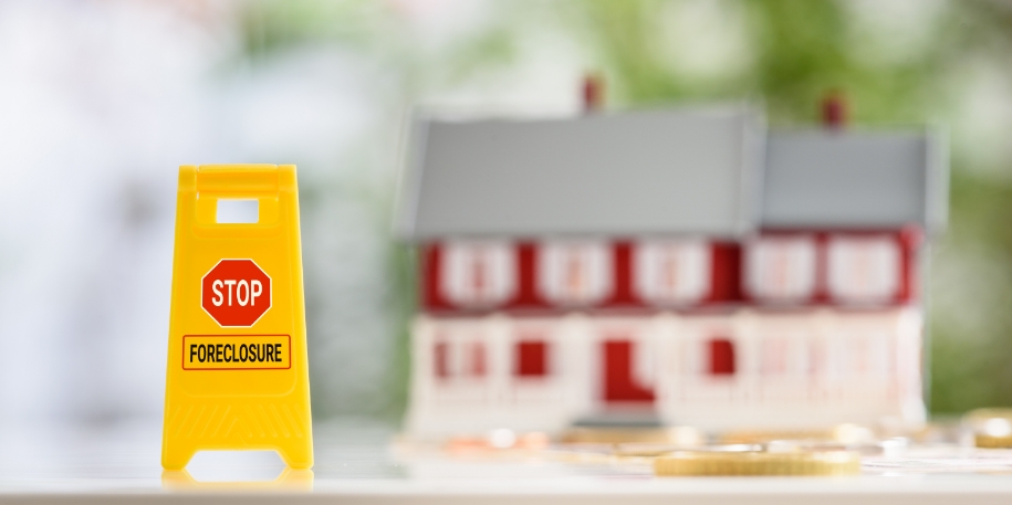 a tiny model home sits in the background, with coins and a 'stop foreclosure' sign in the foreground